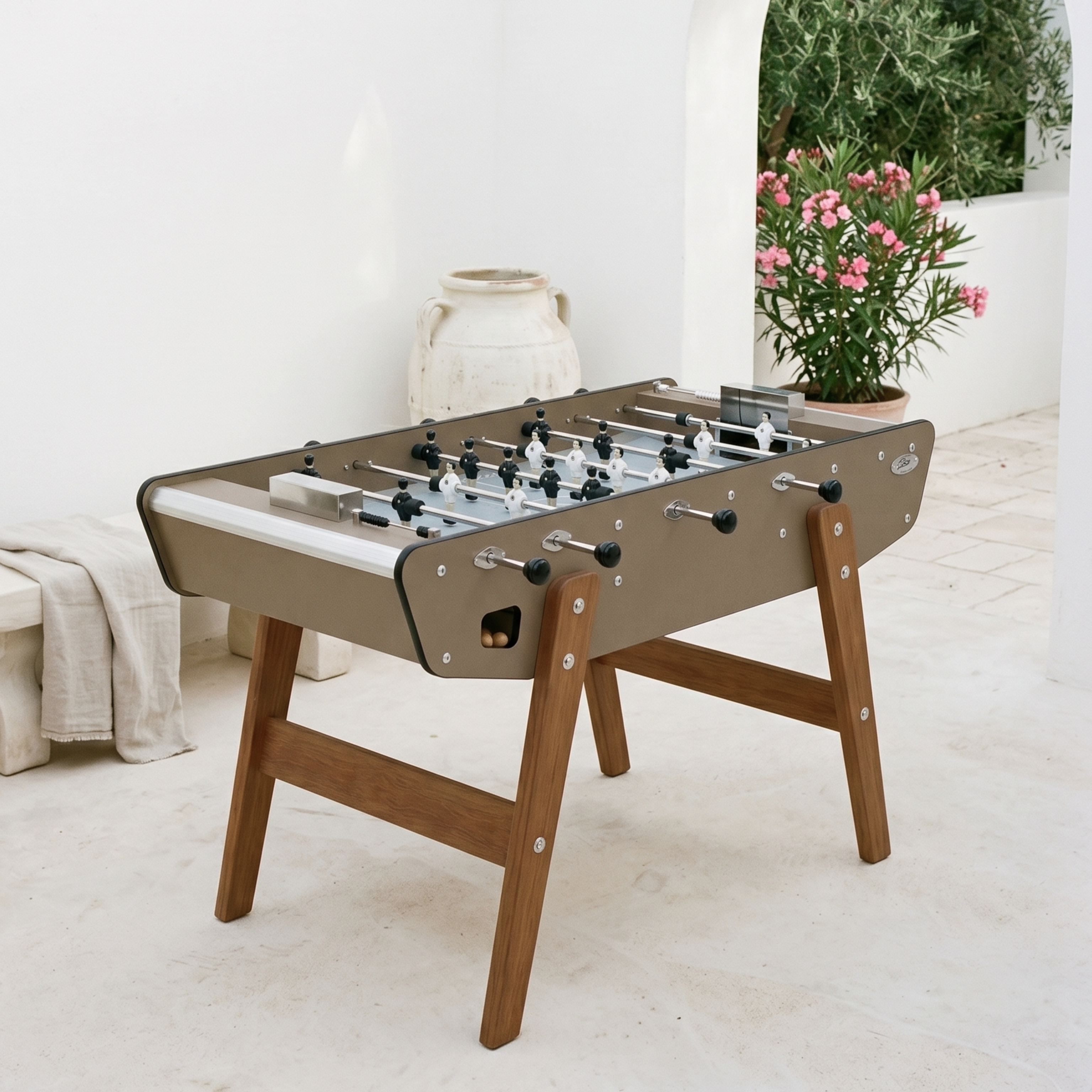 Baby-foot d'extérieur Stella Home Outdoor coloris taupe installé sur une terrasse moderne, finition élégante et intemporelle pour un espace extérieur raffiné et convivial toute l'année.